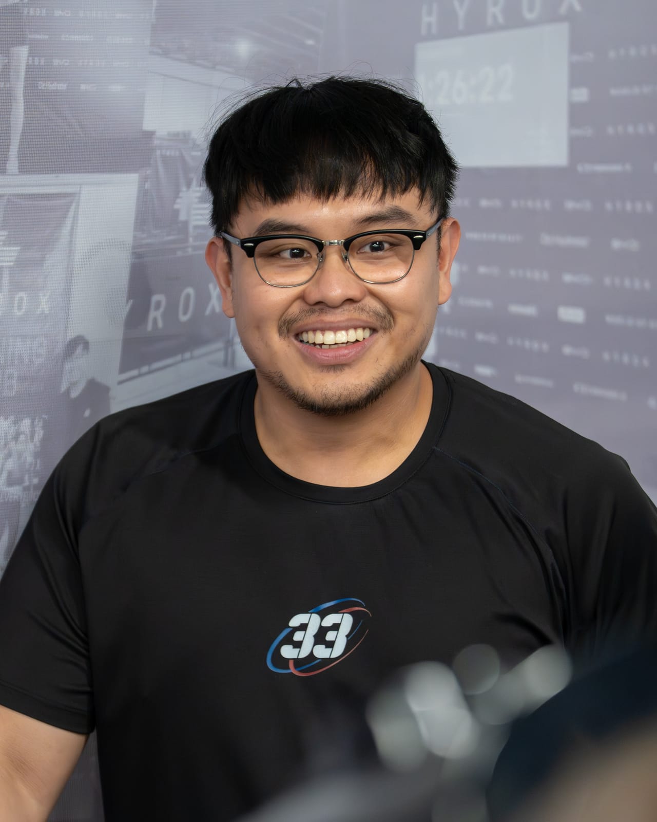 Hoop33 strength and conditioning coach Elijah Briones in the gym by the HYROX wall