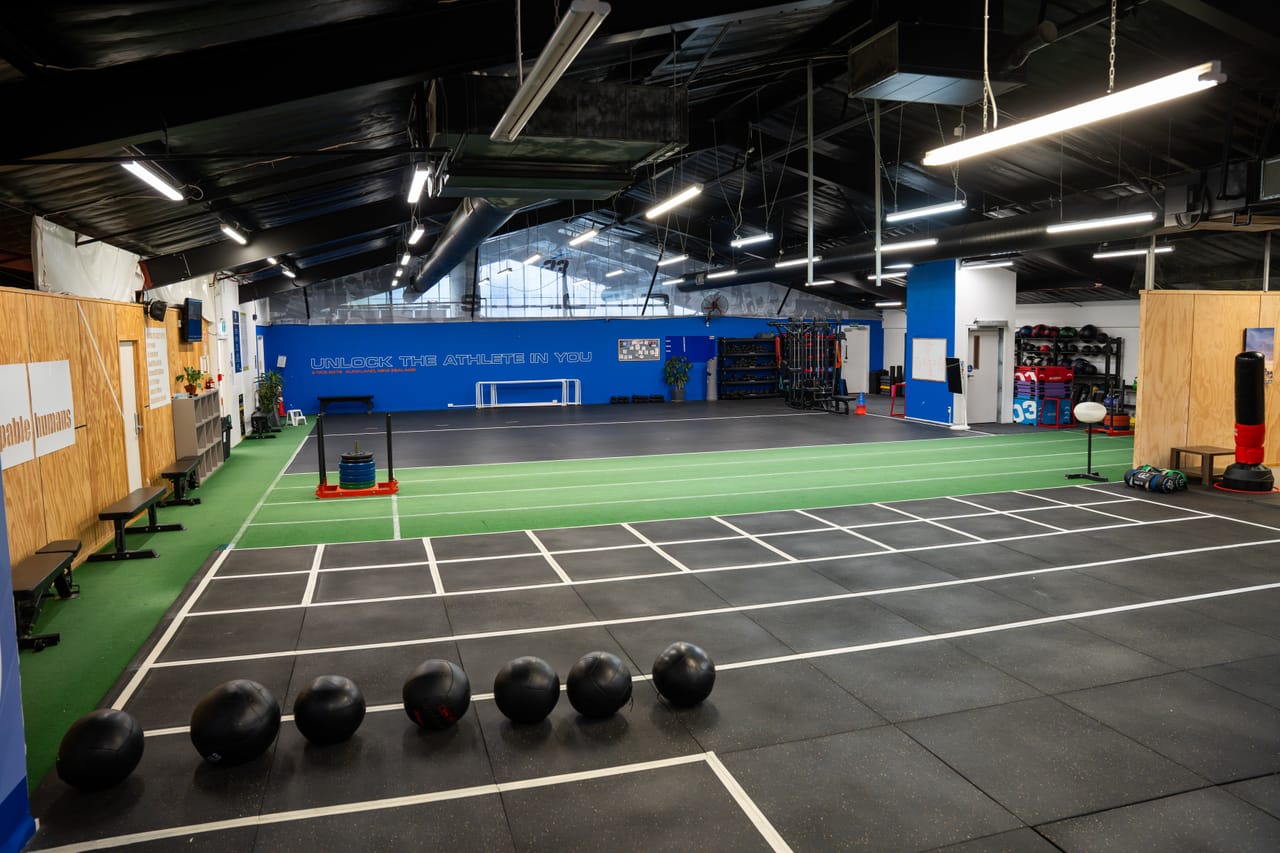 The Hoop33 athletic training room — turf sprint lane, agility grid and the "Unlock the athlete in you" wall