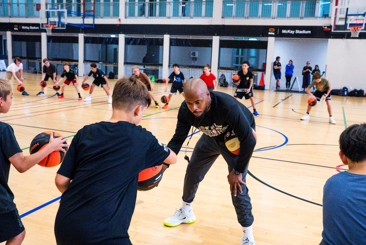 A Hoop33 skills camp — a coach demonstrating to a circle of young players