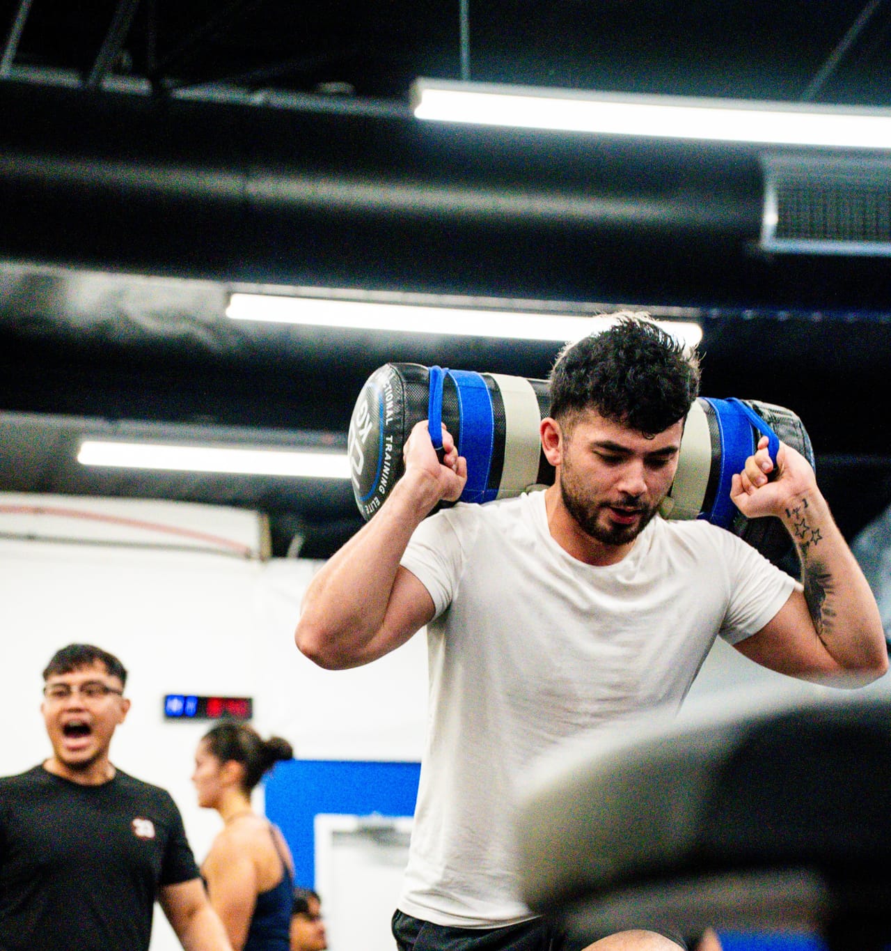 A Hoop33 member carrying a sandbag across his shoulders during a HYROX session